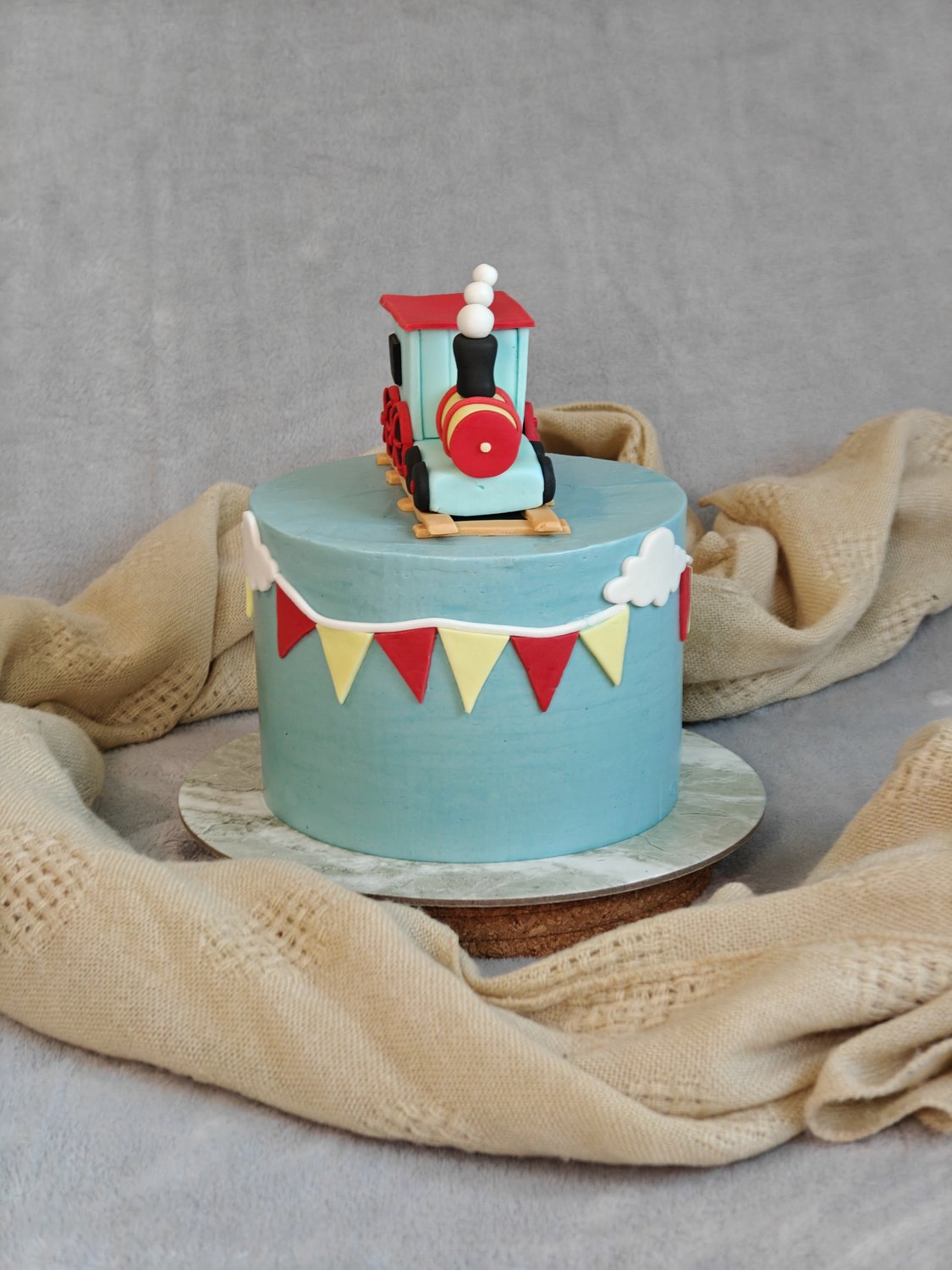 Sky blue fondant train cake with colorful bunting and handcrafted locomotive